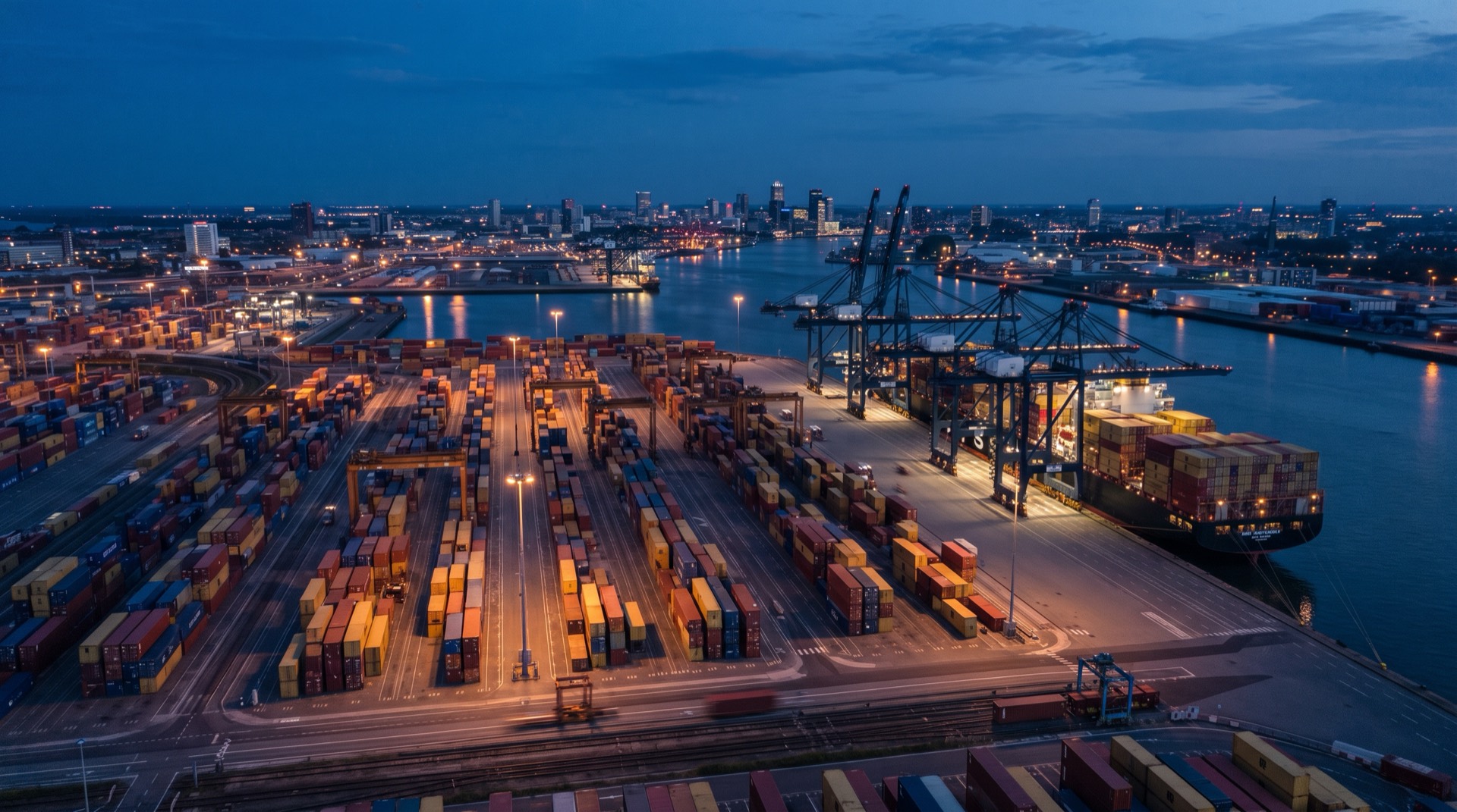 Containerterminal zur blauen Stunde mit Portalkranen und liegendem Containerschiff